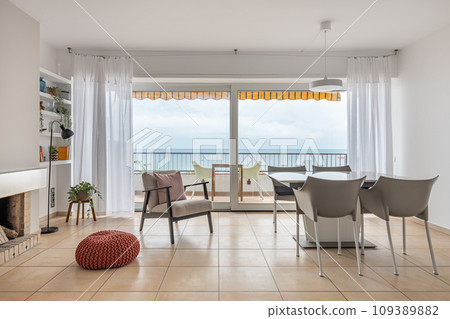 Table and soft armchair near terrace with panoramic window 109389882