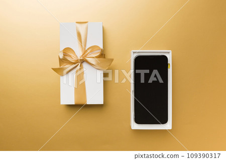 Opened gift box with gold ribbon and smartphone on color background, top view. Blank open box packaging mockup , Template for your design - branding mockup Opened gift box with gold ribbon and smartphone on color background, top view. Blank open box packaging mockup , Template for your design - branding mockup 109390317