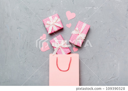 Gift boxes pop out from paper bag top view on colored background. bag packing handmade boxes fall out Concept of holidays, shopping, sale, discounts. Top view, flat lay Gift boxes pop out from paper bag top view on colored background. bag packing handmade boxes fall out Concept of holidays, shopping, sale, discounts. Top view, flat lay 109390328