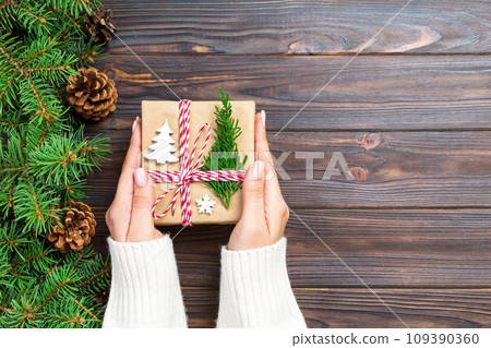 Woman hands give wrapped christmas handmade present in paper top view. Copy space Woman hands give wrapped christmas handmade present in paper top view. Copy space 109390360