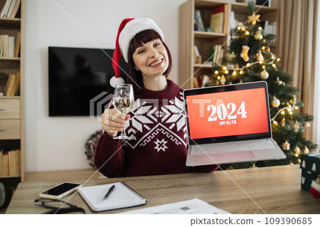 Businesswoman holding glass champagne and laptop with new year congratulations Businesswoman holding glass champagne and laptop with new year congratulations 109390685