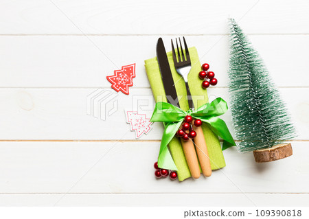 Top view of fork and knife tied up with ribbon on napkin on wooden background. Christmas decorations and New Year tree. Happy holiday concept with empty space for your design 109390818