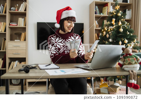 Attractive woman in Santa hat lifting hands with cash papers 109390872