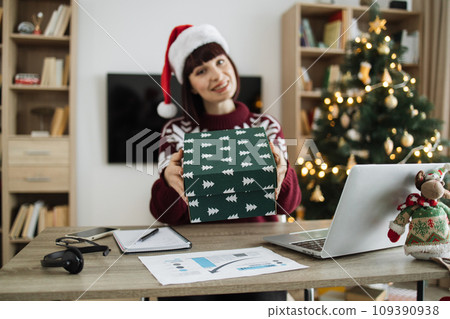 Happy businesswoman in Santa hat and casual clothes offering gift box 109390938