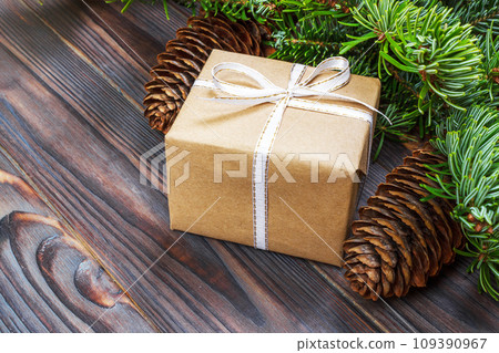 Christmas composition. Christmas gift, knitted blanket, pine cones, fir branches on wooden white background. Flat lay, top view 109390967