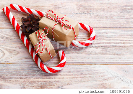 candy canes and christmas gift on brown wooden background candy canes and christmas gift on brown wooden background 109391056