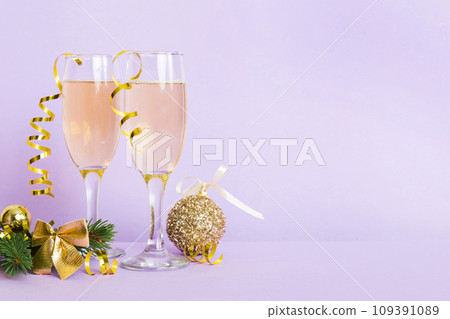 Champagne glasses and christmas decor on colored holiday background. Flat lay New Year decorations Champagne glasses and christmas decor on colored holiday background. Flat lay New Year decorations 109391089