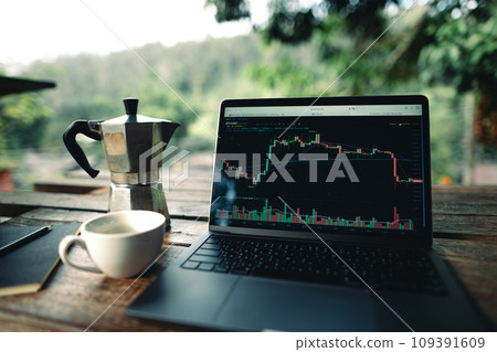 Laptop on table with coffee and stock graphs 109391609