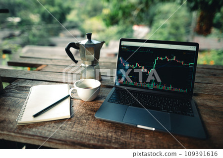 Laptop on table with coffee and stock graphs 109391616