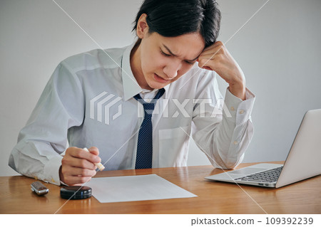 一名年輕人在一份文件上蓋章，一臉苦相 109392239