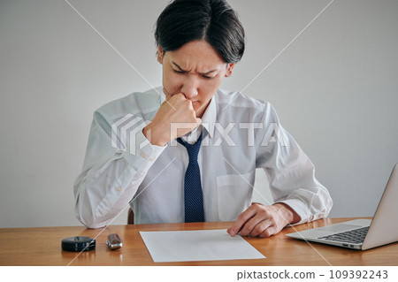 A young man looking through documents with a frowning expression A young man looking through documents with a frowning expression 109392243