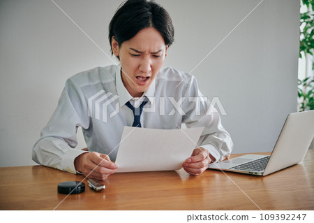 A young male office worker looks surprised when he looks at the documents. A young male office worker looks surprised when he looks at the documents. 109392247