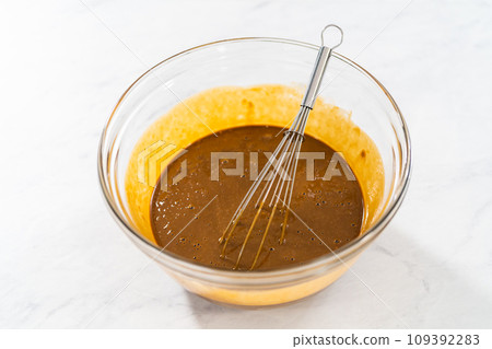 Mixing wet ingredients in a small glass mixing bowl to bake gingerbread bundt cake with caramel filling Mixing wet ingredients in a small glass mixing bowl to bake gingerbread bundt cake with caramel filling 109392283