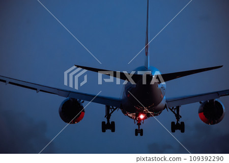 A passenger plane landing while reflecting its approach lights at night A passenger plane landing while reflecting its approach lights at night 109392290