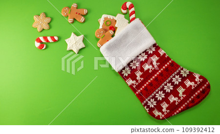 Christmas sock with gingerbread and christmas on green background 109392412