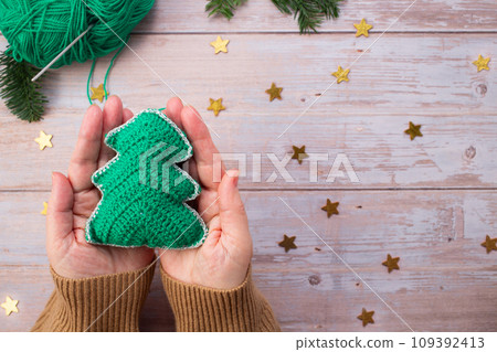 Knitted Christmas tree in woman hands. Close-up. Handmade Christmas gifts 109392413
