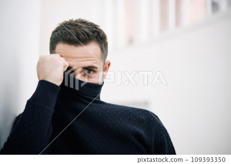Young handsome man hiding behind turtleneck. Young handsome man hiding behind turtleneck. 109393350