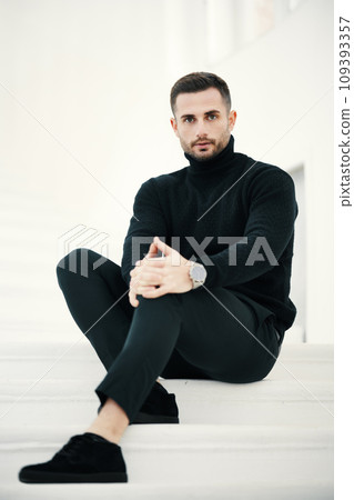 Fashionable man seated on white staircase Fashionable man seated on white staircase 109393357