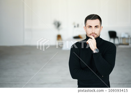 Thoughtful man in stylish clothing outfit looking to camera with copy space over modern interior background 109393415