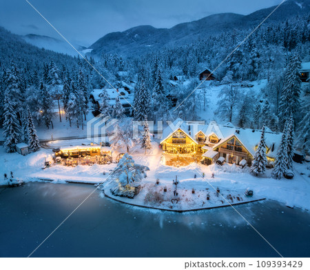 Aerial view of illuminated houses in snowy village at night Aerial view of illuminated houses in snowy village at night 109393429
