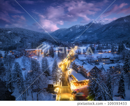Aerial view of road, snowy mountains, street lights at night 109393433