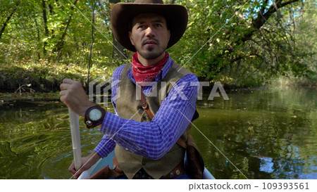 Cowboy in a canoe floats on the river in the forest 109393561