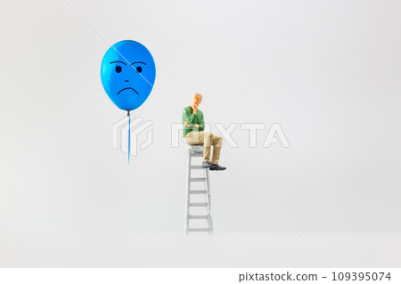 Miniature people, A despondent businessman with a blue balloon is sitting on a staircase. , Blue monday concept. Miniature people, A despondent businessman with a blue balloon is sitting on a staircase. , Blue monday concept. 109395074