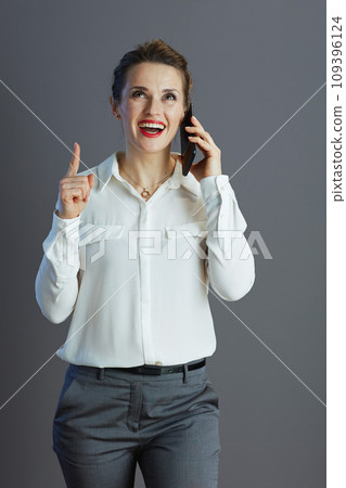 happy elegant female employee pointing up and talking on phone happy elegant female employee pointing up and talking on phone 109396124