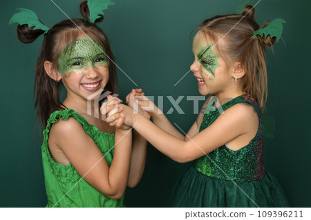 Laughing funny children with makeup in the guise of a dragon play together. New Year of the Dragon according to the Chinese calendar Laughing funny children with makeup in the guise of a dragon play together. New Year of the Dragon according to the Chinese calendar 109396211