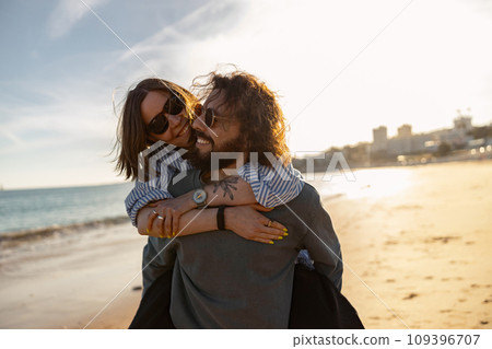 Handsome couple in love hugging while walking along the beach on sunny day Handsome couple in love hugging while walking along the beach on sunny day 109396707