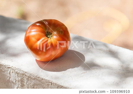 One big tomato on the concrete wall on the blurred natural background, copy space 109396910