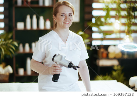 happy female massage therapist in spa salon with massage pistol 109397128