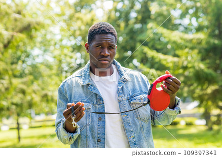 latin american man holding a leash of missing at sunny day in city park latin american man holding a leash of missing at sunny day in city park 109397341