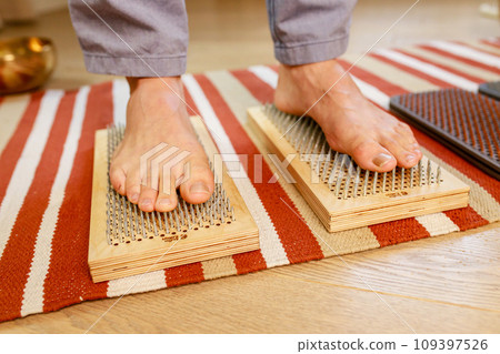 morning yoga practice with sadhu nails. mans foot on the wooden desk with sharp metal nails 109397526