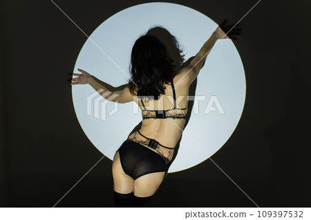 Black and white photo of a beautiful young woman in lace lingerie with a shadow pattern on the face and body in the form of circle Black and white photo of a beautiful young woman in lace lingerie with a shadow pattern on the face and body in the form of circle 109397532