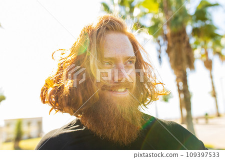 handsome redhaireb man with long beard wear black sporty suit and warming up in sunny beach 109397533