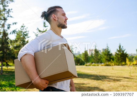 Man in white blazer holding cardboard boxes outdoor in summer park Man in white blazer holding cardboard boxes outdoor in summer park 109397707
