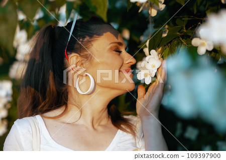 happy elegant female in white shirt near flowering tree happy elegant female in white shirt near flowering tree 109397900