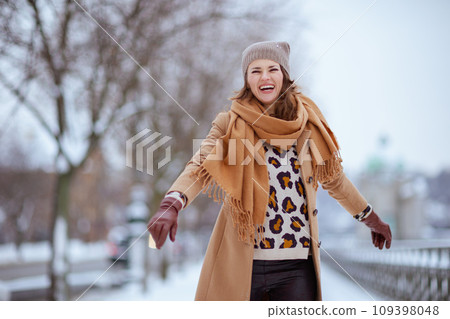 smiling elegant female in brown hat and scarf in camel coat smiling elegant female in brown hat and scarf in camel coat 109398048