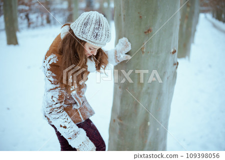 modern female in brown hat and scarf shaking snow off clothes modern female in brown hat and scarf shaking snow off clothes 109398056