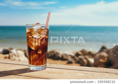Soda drink with ice in glass on wooden table, sea on background 109398210