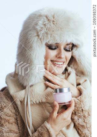 smiling stylish woman in winter coat and fur hat on white 109398372