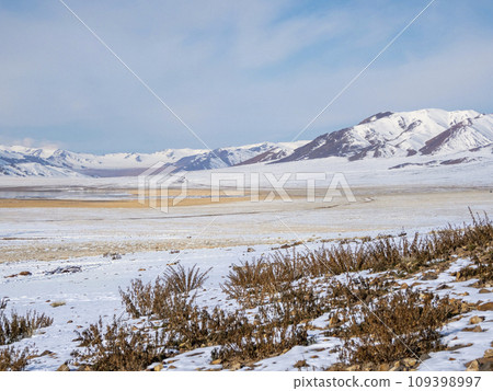 Snow mountain in Mongolia. Scenic landscape with snowy mountain top. Wonderful view from stony snowy mountain to mountain range under blue sky in sunny day. Snow mountain in Mongolia. Scenic landscape with snowy mountain top. Wonderful view from stony snowy mountain to mountain range under blue sky in sunny day. 109398997