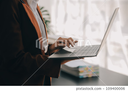 Attractive smiling young asian business woman work at home office, Asian woman working on laptop computer holding tablet. 109400006