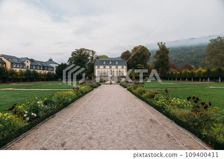 Orangery in middle of lawn with planted flowers among nature Orangery in middle of lawn with planted flowers among nature 109400411