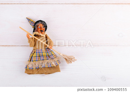 The witch Befana on white wooden background, top view, copy space 109400555
