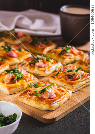 Mini pizza with sausages, tomatoes, cheese and herbs on a wooden board on the table vertical view Mini pizza with sausages, tomatoes, cheese and herbs on a wooden board on the table vertical view 109400652