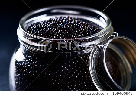 Closeup of natural black caviar in jar on black background, texture of luxury fresh sturgeon caviar macro photo. Closeup of natural black caviar in jar on black background, texture of luxury fresh sturgeon caviar macro photo. 109400945