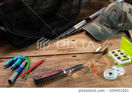 Folding knife and fishing tools. Fishing rod and tackle. Fishing composition on a wooden platform. 109401081