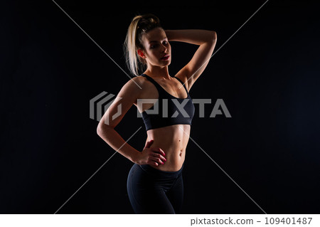 Beautiful young woman dressed in sports uniform, posing in studio on a yellow red dark background. Beautiful young woman dressed in sports uniform, posing in studio on a yellow red dark background. 109401487